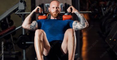 Man doing quadriceps exercise on hack squat machine at gym