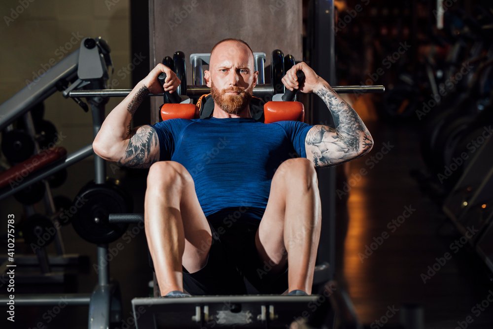 Man doing quadriceps exercise on hack squat machine at gym