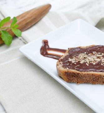 Nocilla toast with dried fruit. Wooden spoon background.