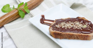 Nocilla toast with dried fruit. Wooden spoon background.