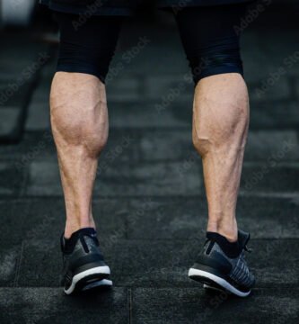 trained legs with muscular calves in sneakers in training gym during hard fitness and crossfit workout