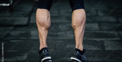 trained legs with muscular calves in sneakers in training gym during hard fitness and crossfit workout